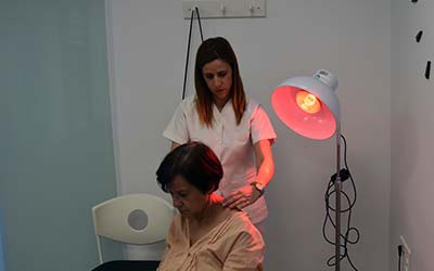 Sesión de fisioterapia con la aplicación de masoterapia con lámpara de infrarrojos.